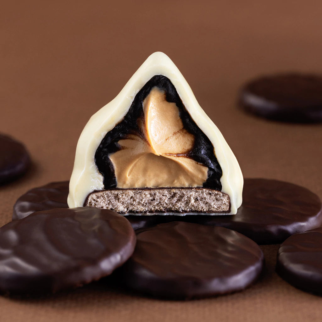 Close-up of a layered dessert with white, black, and brown layers on a brown background